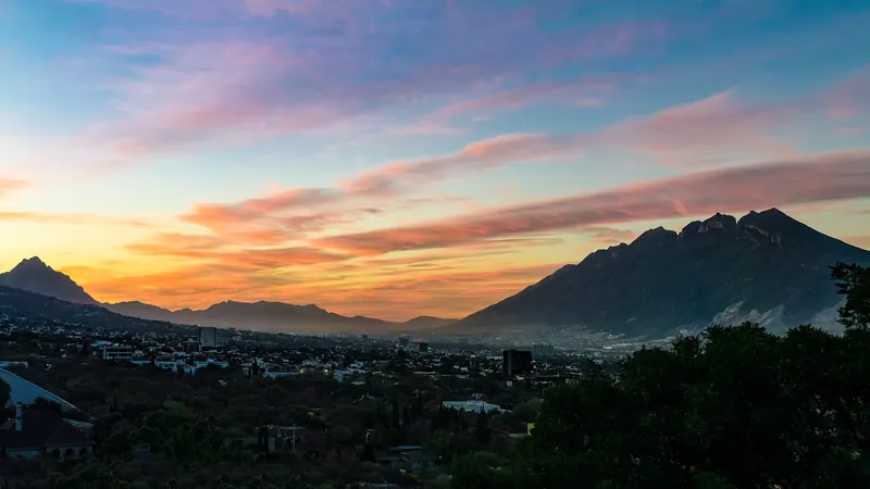 Cielo naranja y rosa del atardecer sobre la sierra que rodea Monterrey, visto desde el Parque Fundidora