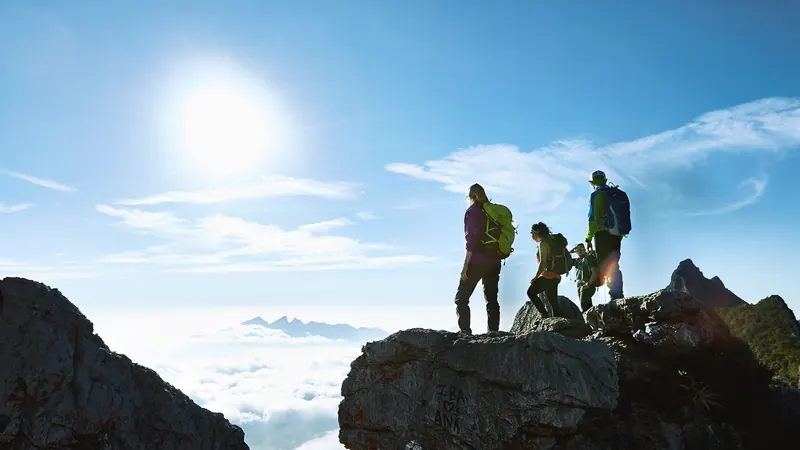Tres excursionistas sobre una roca de la sierra de Chipinque, por encima de un mar de nubes, con el sol de frente