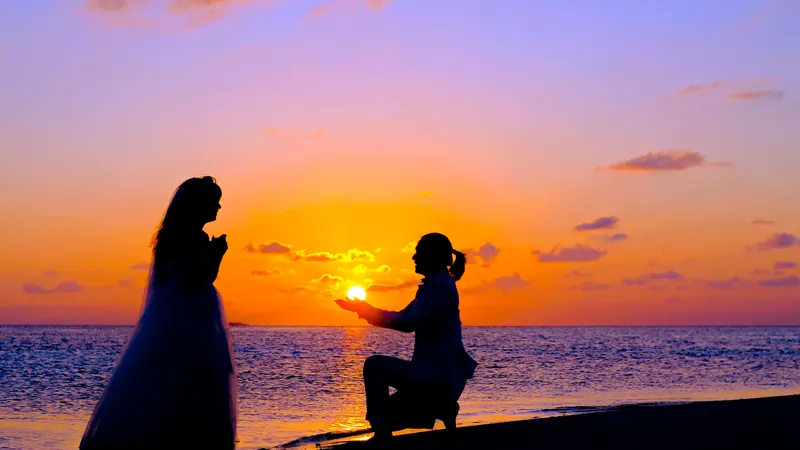 Siluetas de dos personas en la playa con el cielo naranja y morado del amanecer