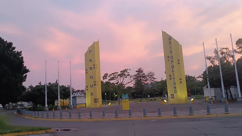 Las dos torres amarillas de la entrada del Parque Metropolitano de Guadalajara bajo un cielo rosa y violeta al atardecer